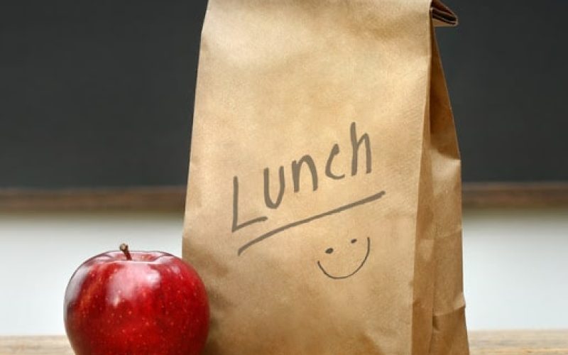 Paper lunch bag on desk with apple